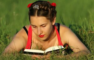 jeune fille lisant dans l'herbe